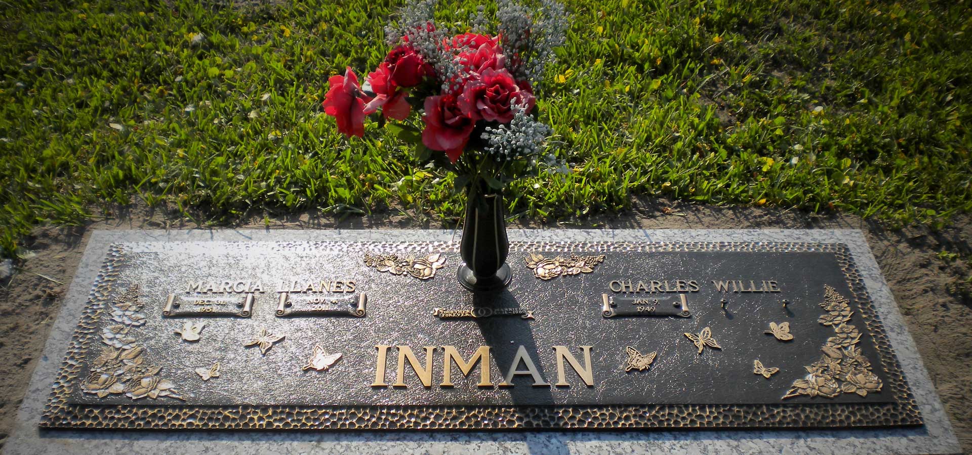 Bronze companion marker with butterflies and roses in relief, set in a granite border with a vase